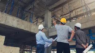 Two men in hard hats are standing on a construction site.