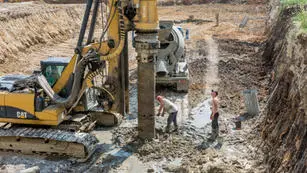 Two men working on a construction site with a large crane.