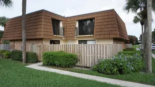 A house with a fence and bushes in front of it