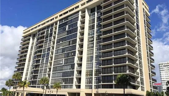 A large building with many windows and palm trees.