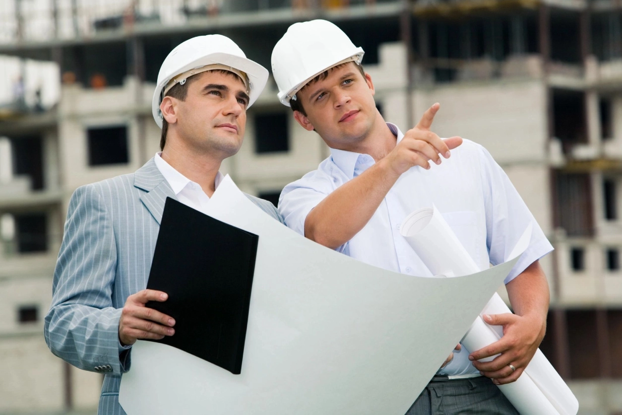 Two men in hard hats looking at a building plan.